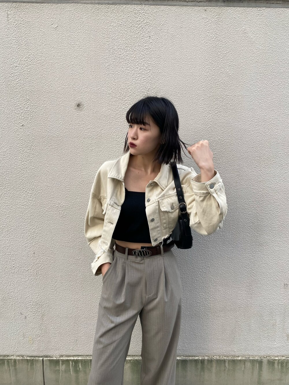 ホワイト系のデニムジャケット、ブラック系のキャミソール、ブラック系のハンドバッグを着用したレディースの春コーディネートの7枚目の写真