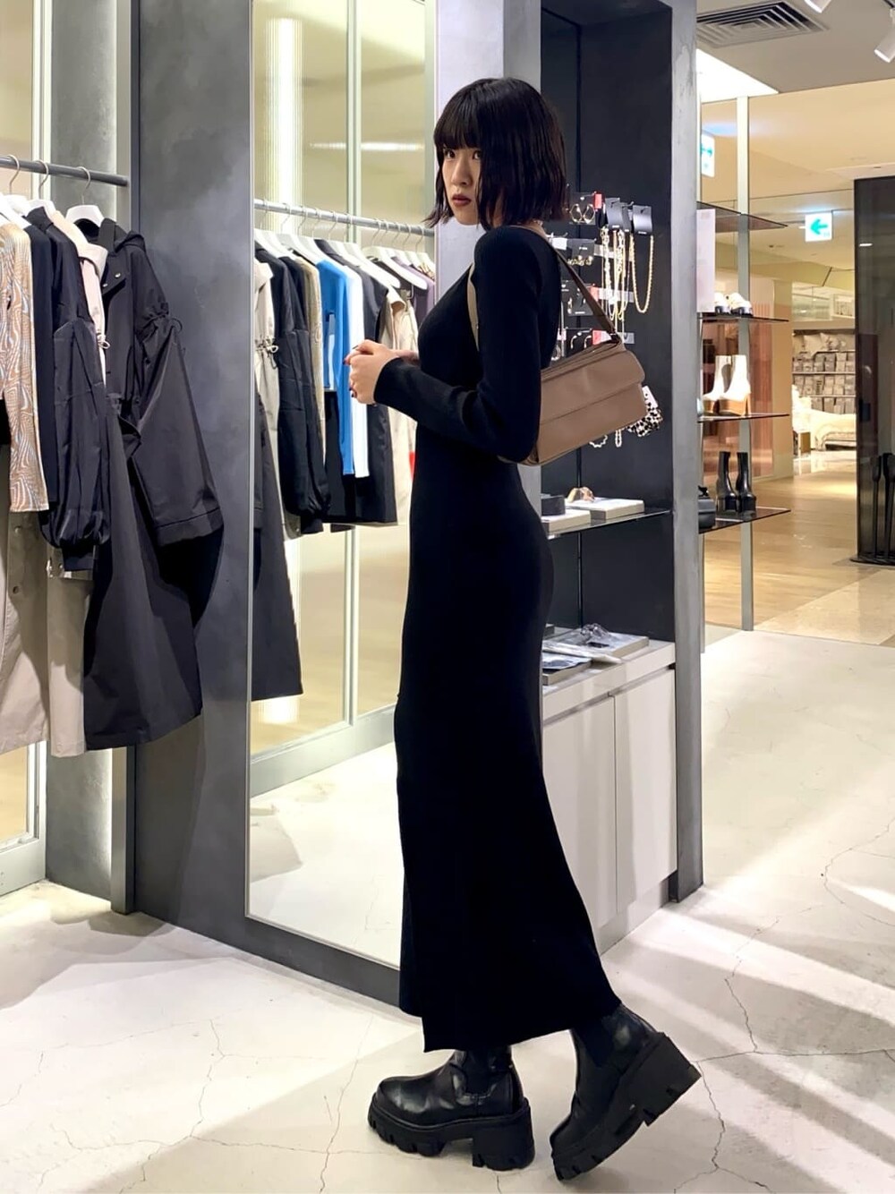 ブラック系のブーツ、ブラック系のワンピース、ブラウン系のハンドバッグを着用したレディースの秋コーディネートの2枚目の写真