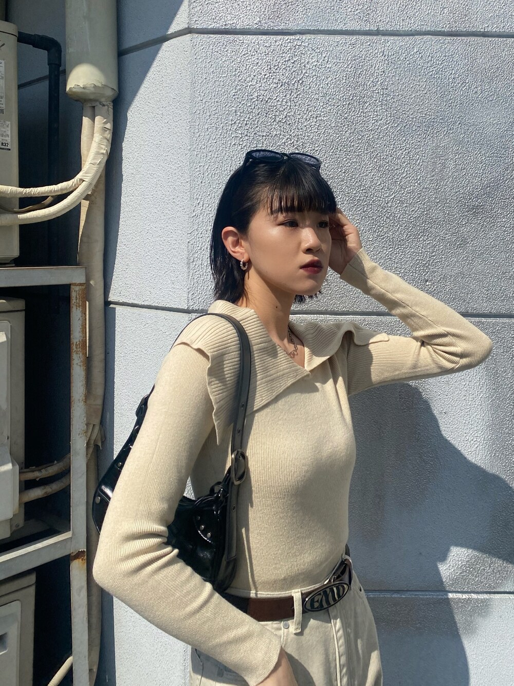 ブラウン系のブーツ、ホワイト系のデニムパンツ、ブラック系のハンドバッグを着用したレディースの春コーディネートの7枚目の写真