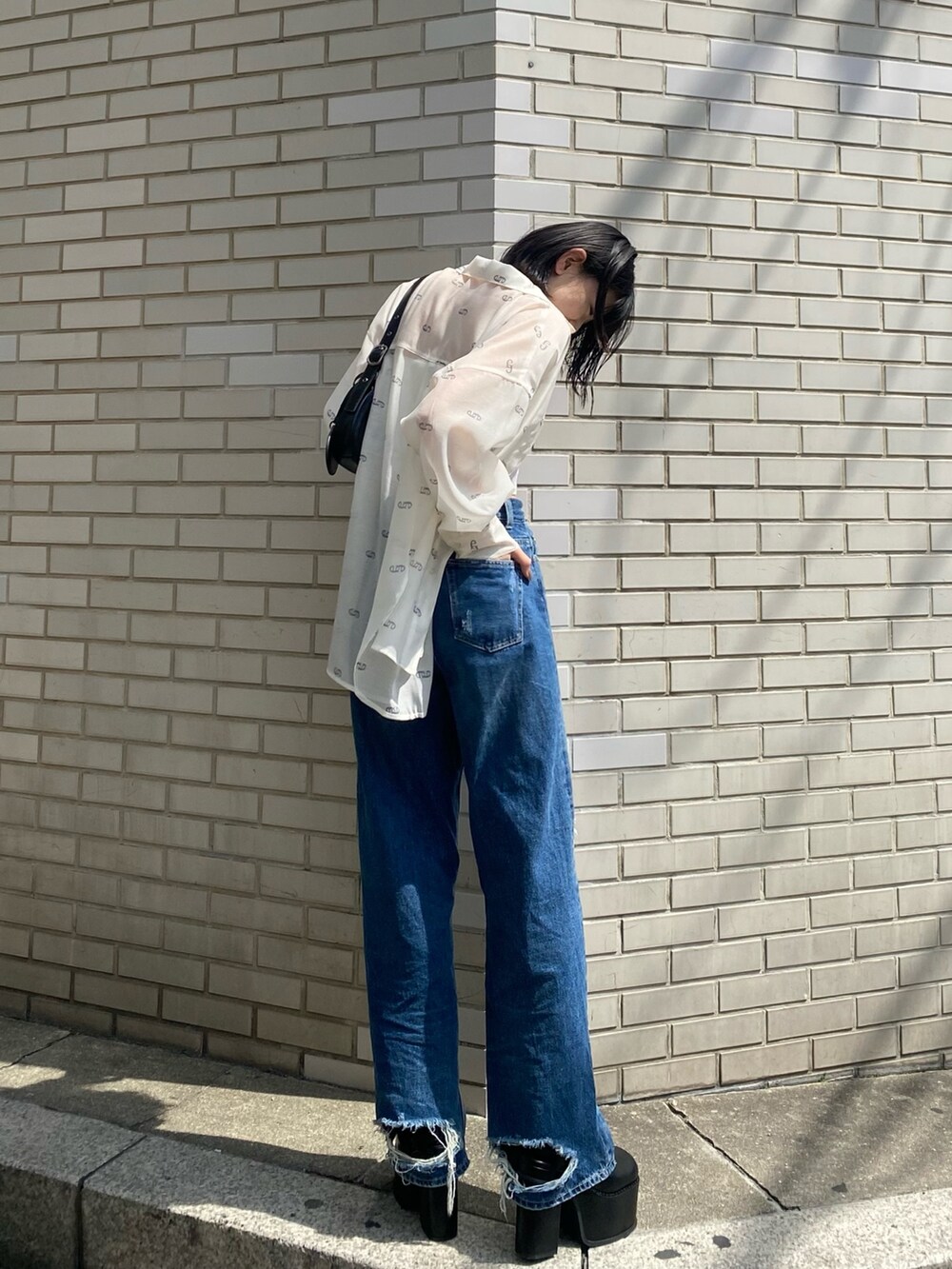 ブラック系のサンダル、ブラック系のハンドバッグ、ブルー系のデニムパンツを着用したレディースの春コーディネートの5枚目の写真