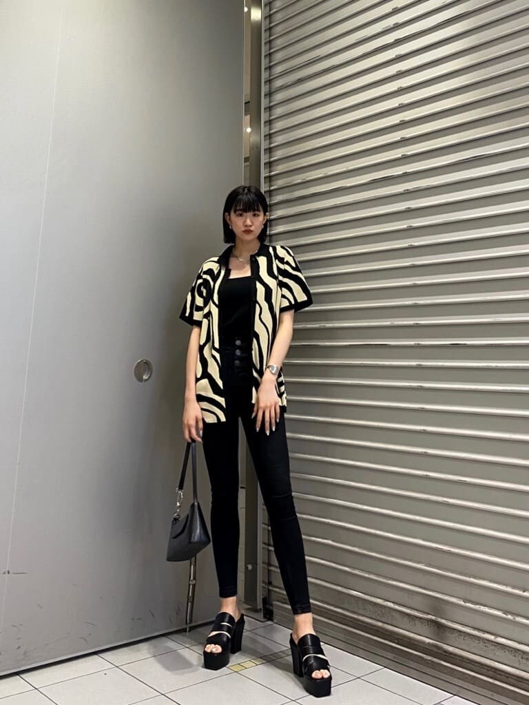 ブラック系のニット/セーター、ブラック系のサンダル、ブラック系のデニムパンツを着用したレディースの夏コーディネートの2枚目の写真