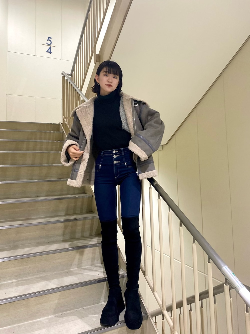 ブルー系のデニムパンツ、グレー系のブルゾン、ブラック系のニット/セーターを着用したレディースの冬コーディネートの2枚目の写真