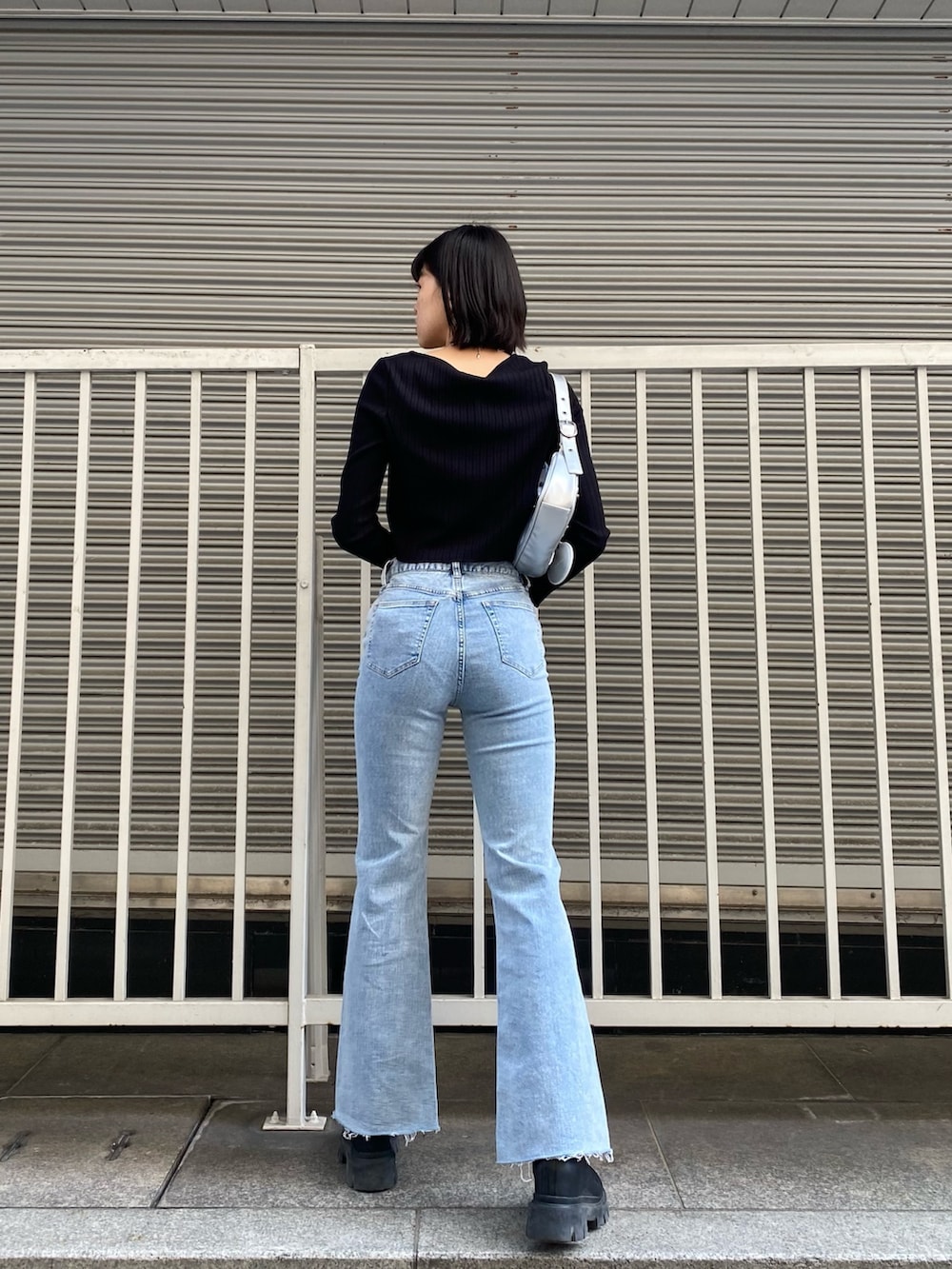 ブルー系のデニムパンツ、ブラック系のTシャツ/カットソー、シルバー系のハンドバッグを着用したレディースの春コーディネートの3枚目の写真