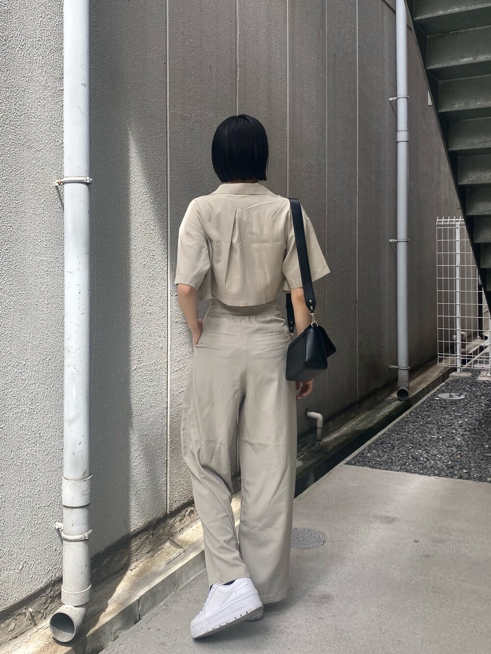 ベージュ系のその他パンツ、ホワイト系のキャミソール、ベージュ系のショルダーバッグを着用したレディースの夏コーディネートの5枚目の写真