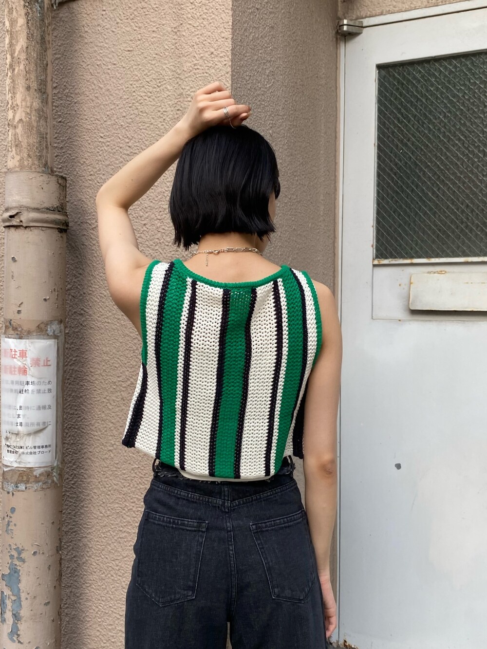 ブラック系のデニムパンツ、ブラック系のブーツ、ブラック系のハンドバッグを着用したレディースの春コーディネートの6枚目の写真