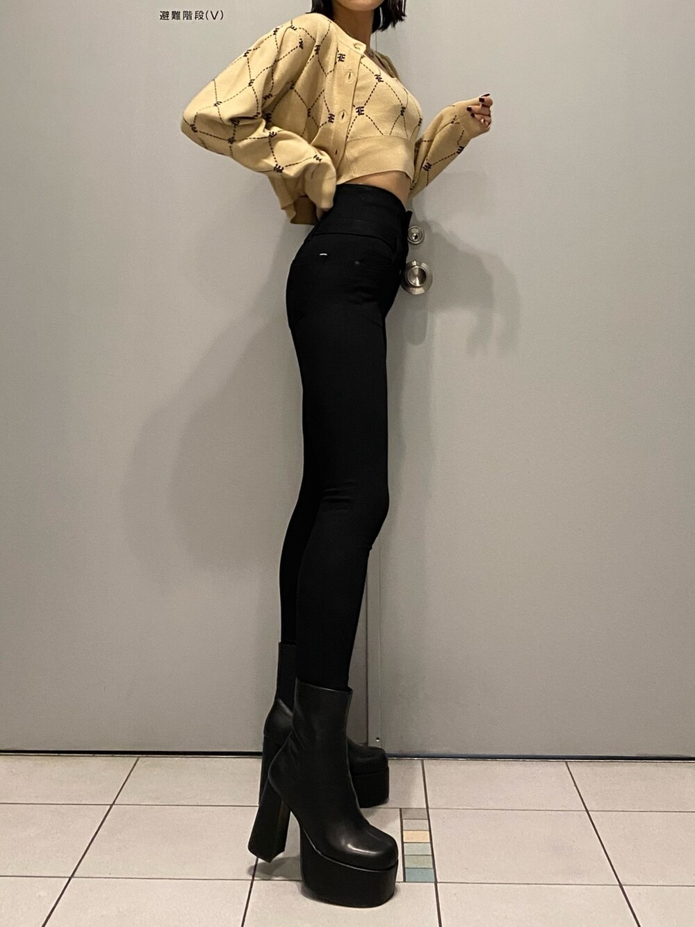 ブラック系のブーツ、ブラック系のデニムパンツ、ベージュ系のニット/セーターを着用したレディースの秋コーディネートの4枚目の写真