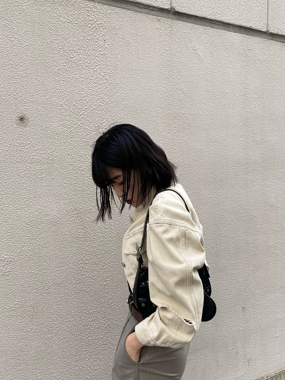 ホワイト系のデニムジャケット、ブラック系のキャミソール、ブラック系のハンドバッグを着用したレディースの春コーディネートの8枚目の写真