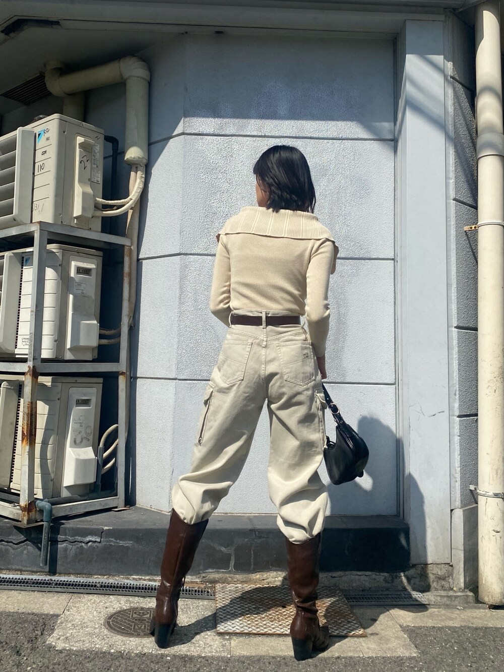 ブラウン系のブーツ、ホワイト系のデニムパンツ、ブラック系のハンドバッグを着用したレディースの春コーディネートの3枚目の写真