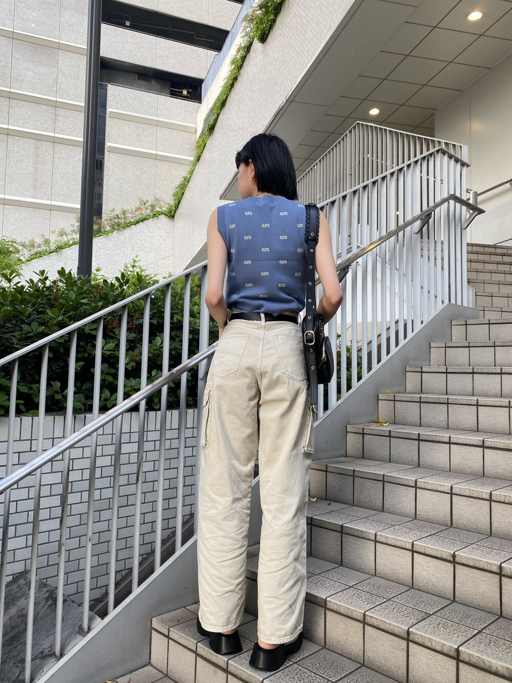 ブラック系のショルダーバッグ、ホワイト系のサンダル、ホワイト系のデニムパンツを着用したレディースの春コーディネートの6枚目の写真