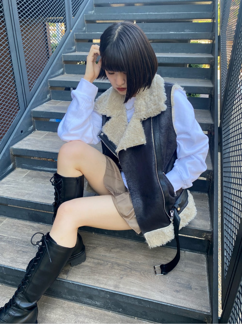 ブラック系のブーツ、ベージュ系のスカート、ブラック系のベストを着用したレディースの秋コーディネートの4枚目の写真