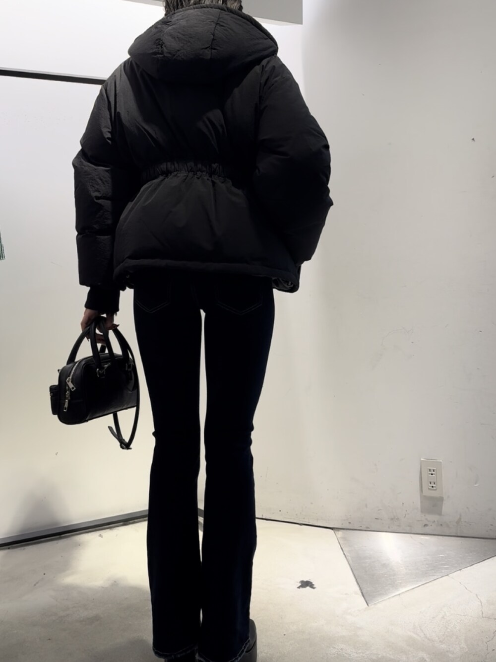 ブラック系のハンドバッグ、ブラック系のニット/セーター、ブルー系のデニムパンツを着用したレディースの冬コーディネートの4枚目の写真