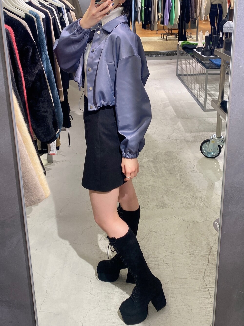 ブラック系のスカート、ブラック系のブーツ、グレー系のブルゾンを着用したレディースの冬コーディネートの2枚目の写真