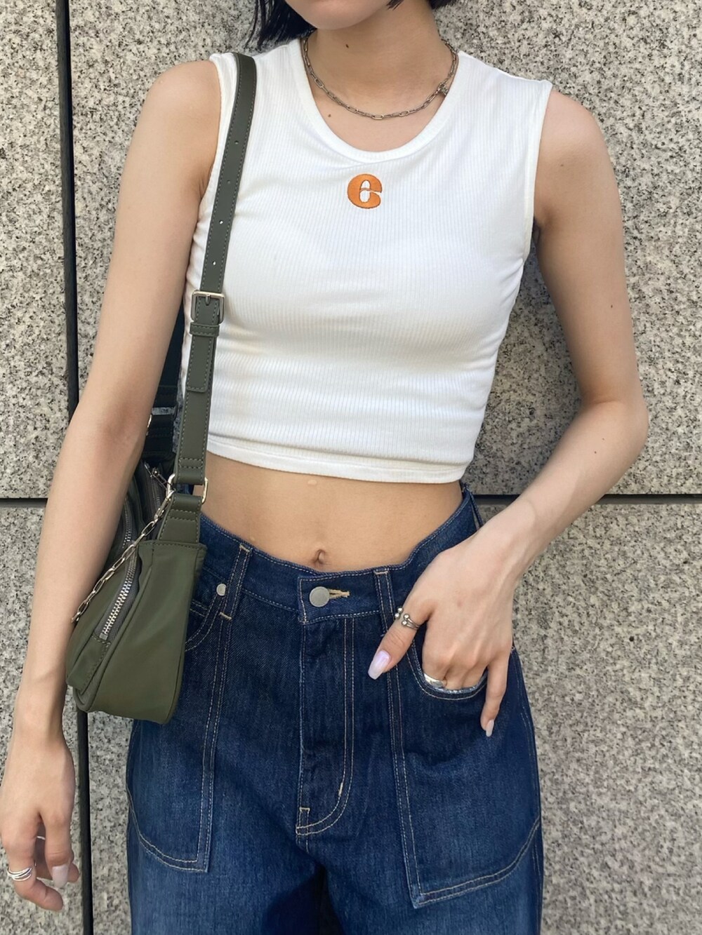 ブラック系のサンダル、ブルー系のデニムパンツ、ホワイト系のタンクトップを着用したレディースの夏コーディネートの5枚目の写真