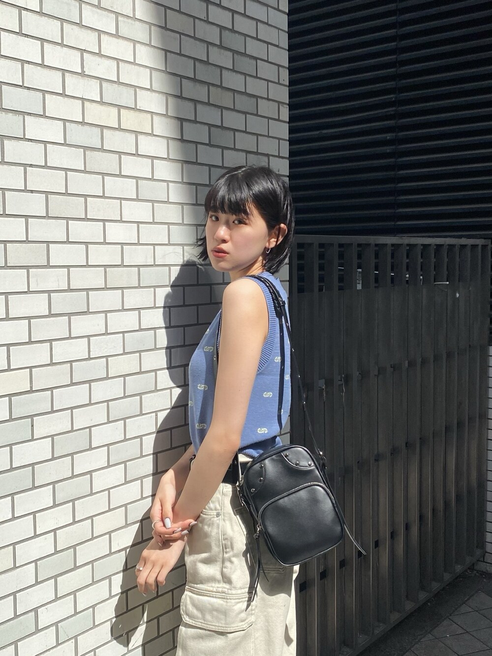 ブラック系のショルダーバッグ、ホワイト系のサンダル、ホワイト系のデニムパンツを着用したレディースの春コーディネートの7枚目の写真