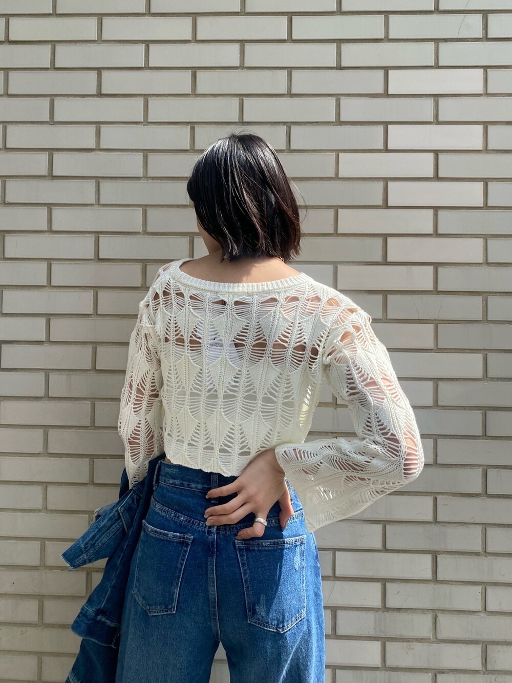 ブラック系のブーツ、ブラック系のハンドバッグ、ブルー系のデニムパンツを着用したレディースの春コーディネートの10枚目の写真