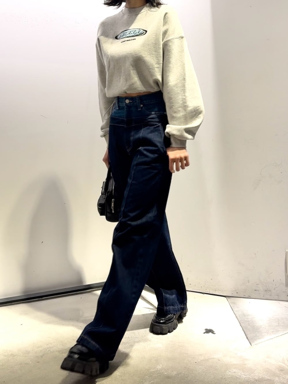 ブルー系のデニムパンツ、ブラック系のハンドバッグ、ブラック系のダウンジャケット/コートを着用したレディースの冬コーディネートの5枚目の写真