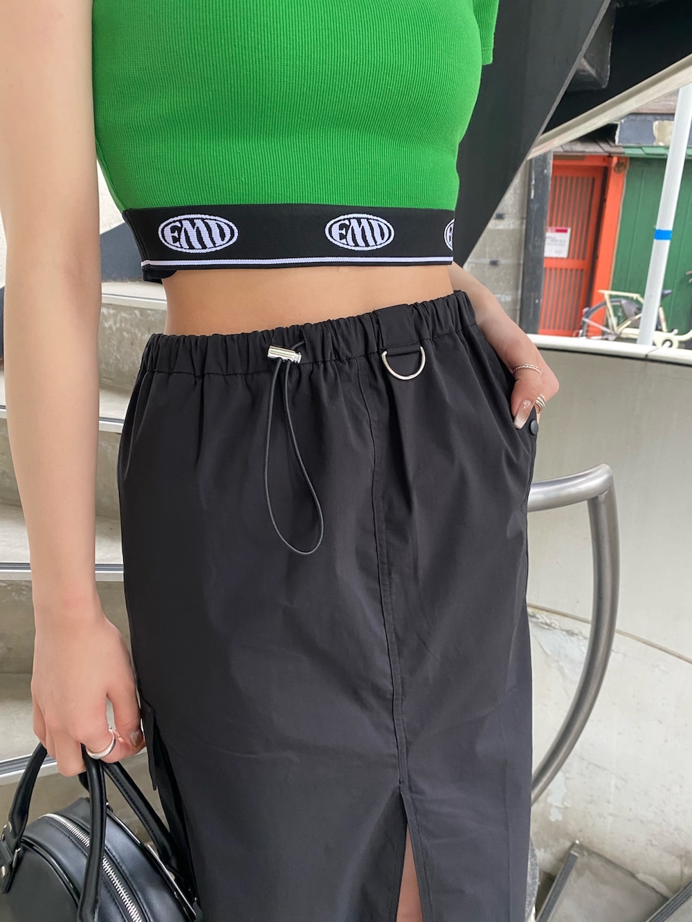 ブラック系のスカート、ブラック系のハンドバッグ、グリーン系のTシャツ/カットソーを着用したレディースの春コーディネートの9枚目の写真