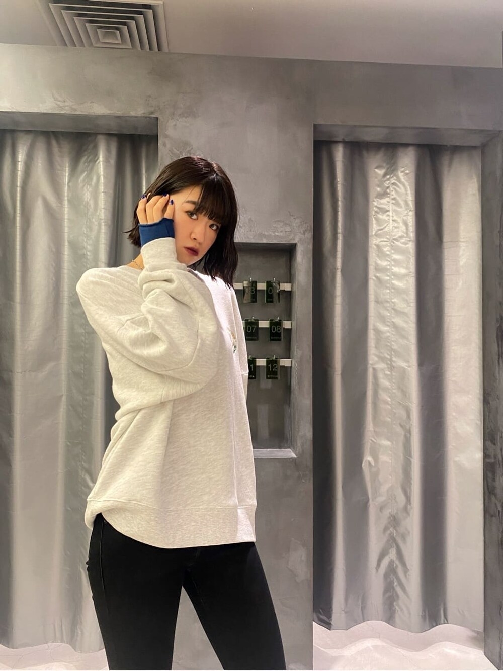 ブラック系のベスト、グレー系のスウェット、ブルー系のアームカバーを着用したレディースの秋コーディネートの3枚目の写真