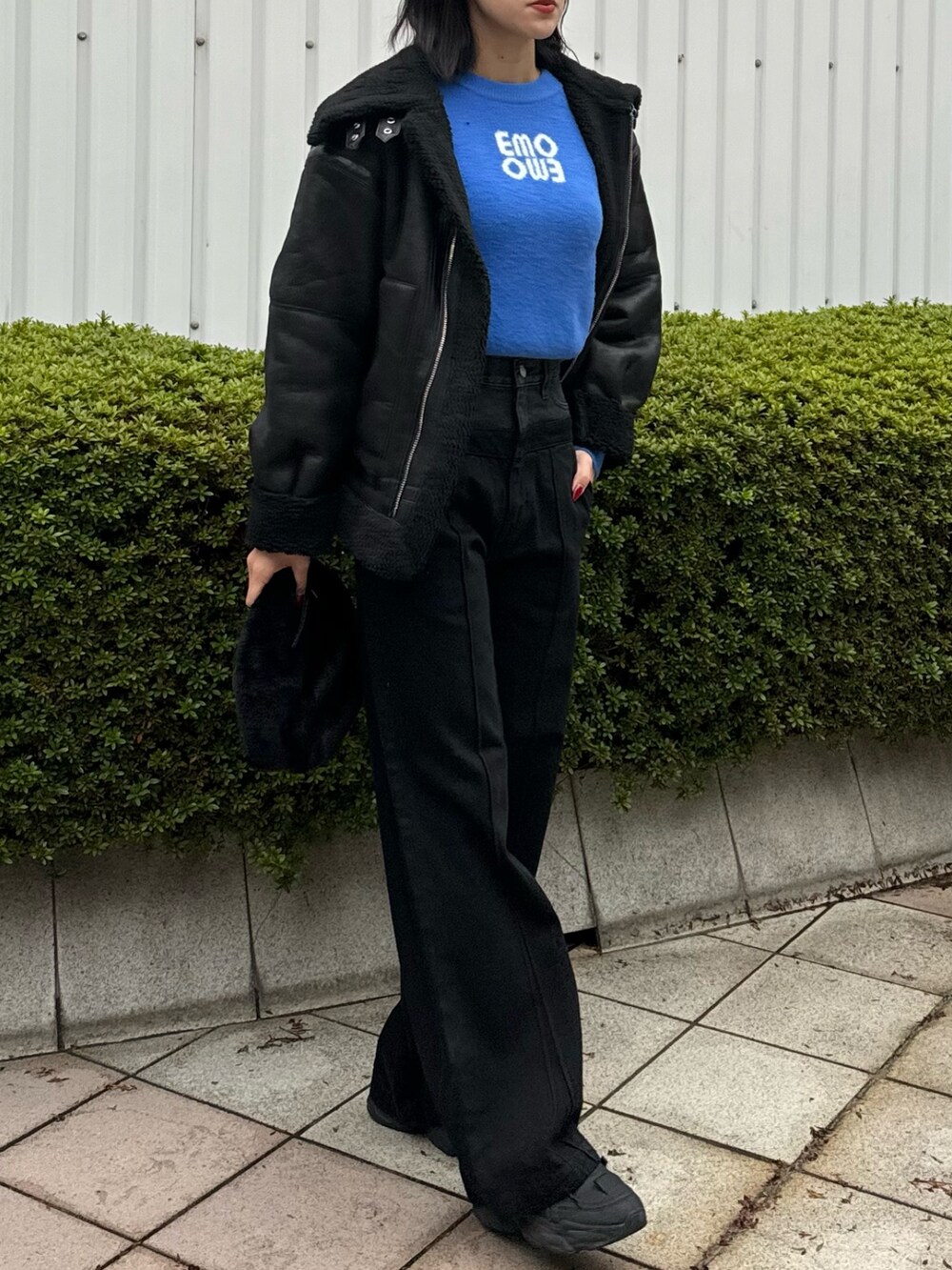 ブラック系のデニムパンツ、ブラック系のハンドバッグ、ブラック系のムートンコートを着用したレディースの冬コーディネートの3枚目の写真