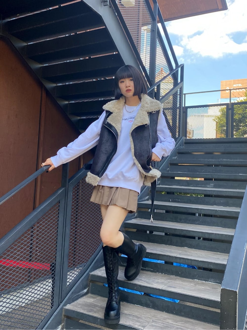 ブラック系のブーツ、ベージュ系のスカート、ブラック系のベストを着用したレディースの秋コーディネートの2枚目の写真