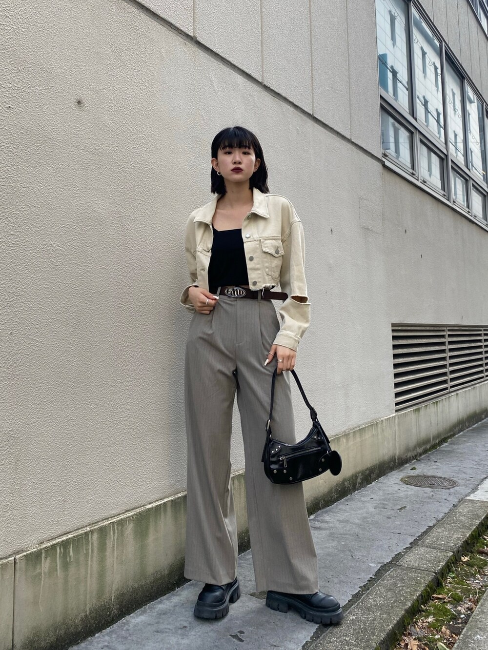 ホワイト系のデニムジャケット、ブラック系のキャミソール、ブラック系のハンドバッグを着用したレディースの春コーディネートの2枚目の写真