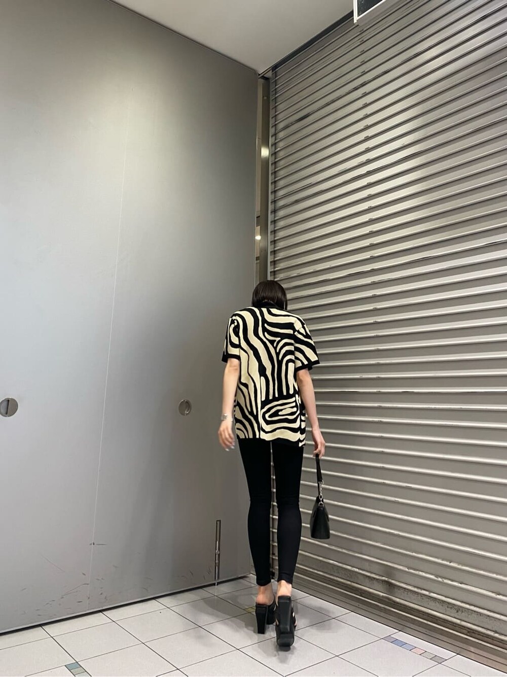 ブラック系のニット/セーター、ブラック系のサンダル、ブラック系のデニムパンツを着用したレディースの夏コーディネートの5枚目の写真