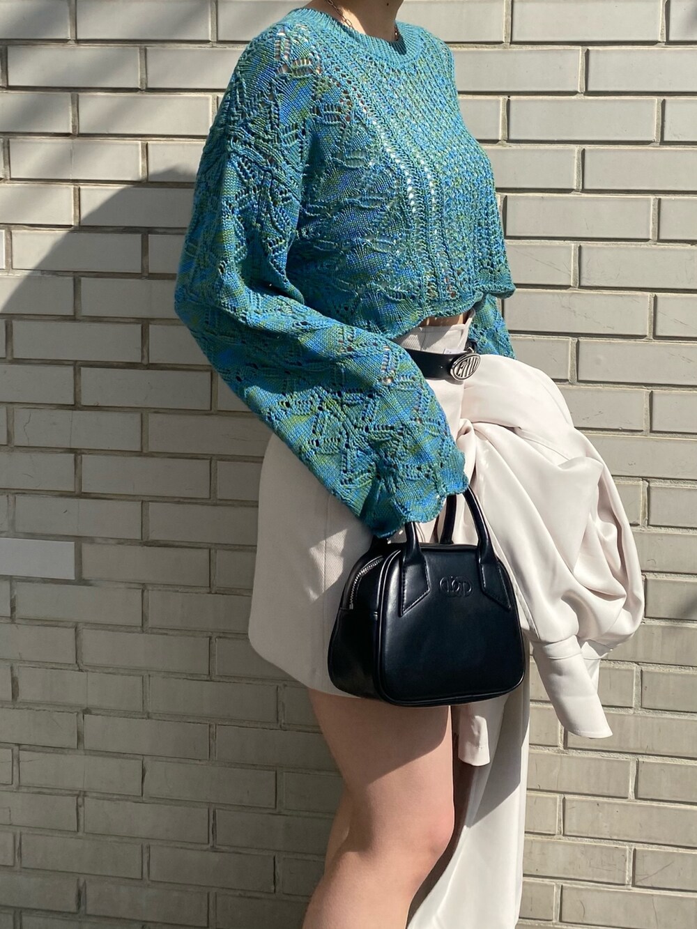 ホワイト系のスカート、ブルー系のニット/セーター、ホワイト系のトレンチコートを着用したレディースの春コーディネートの9枚目の写真