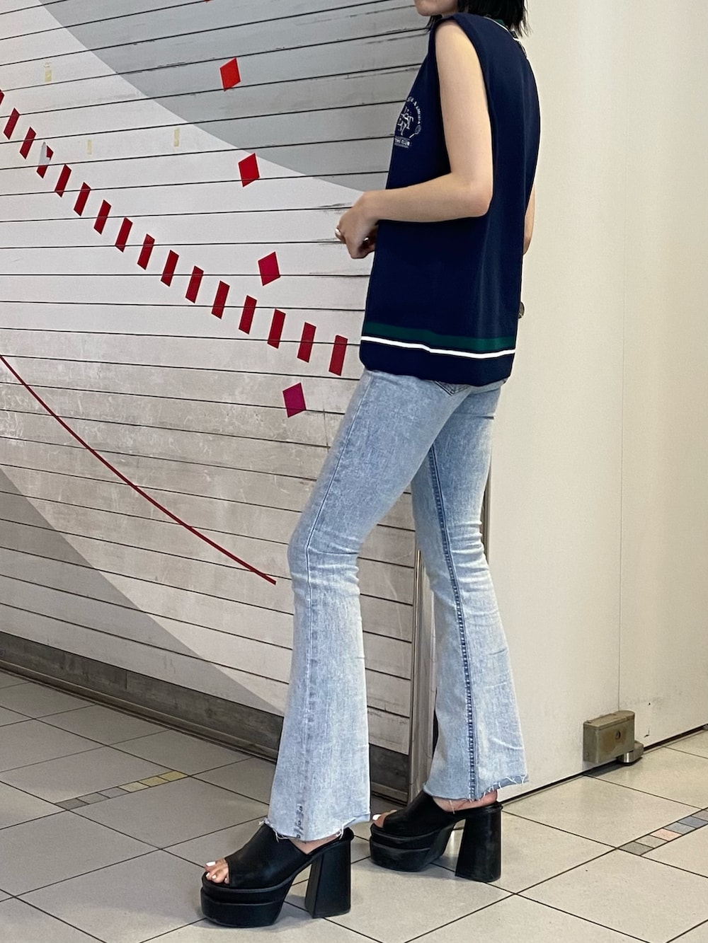 ブラック系のサンダル、ブルー系のデニムパンツ、ブルー系のベストを着用したレディースの春コーディネートの3枚目の写真