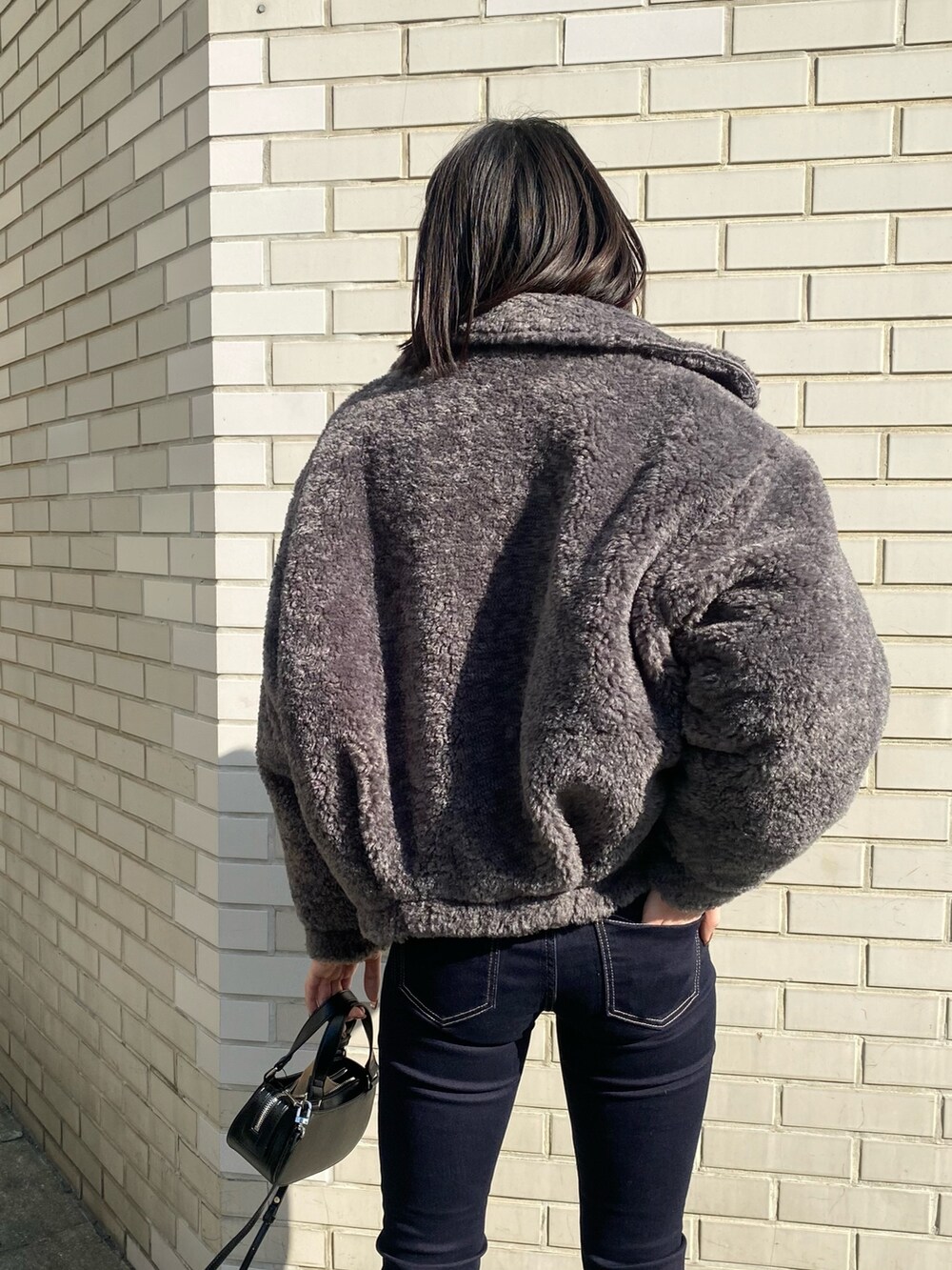 ブラック系のブーツ、ブラック系のハンドバッグ、グレー系のブルゾンを着用したレディースの冬コーディネートの7枚目の写真