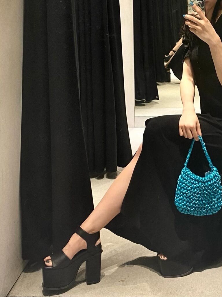 ブラック系のサンダル、ブラック系のワンピース、オレンジ系のハンドバッグを着用したレディースの春コーディネートの2枚目の写真