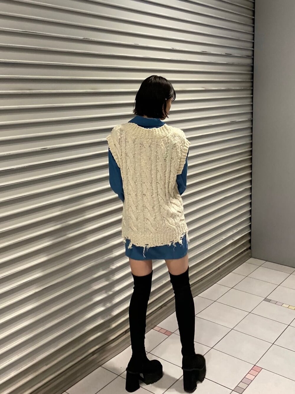 ホワイト系のベスト、ブルー系のワンピース、ブラック系のブーツを着用したレディースの夏コーディネートの5枚目の写真