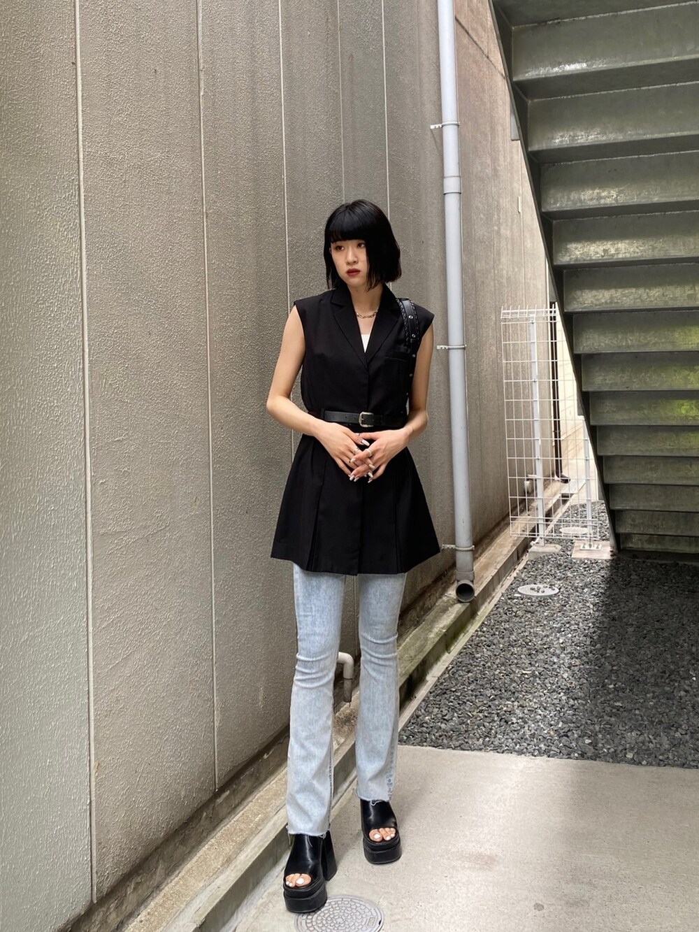 ブラック系のワンピース、ブラック系のサンダル、ブルー系のデニムパンツを着用したレディースの夏コーディネートの2枚目の写真