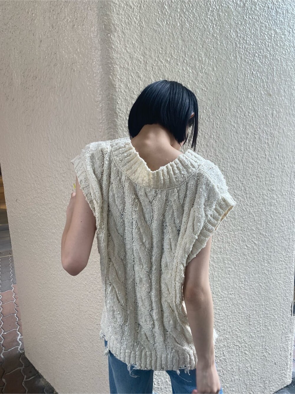 ブルー系のデニムパンツ、ベージュ系のスリッポン、ホワイト系のベストを着用したレディースの夏コーディネートの3枚目の写真