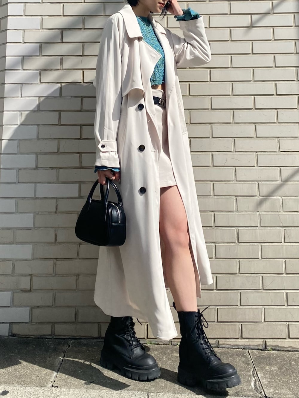 ホワイト系のスカート、ブルー系のニット/セーター、ホワイト系のトレンチコートを着用したレディースの春コーディネートの5枚目の写真