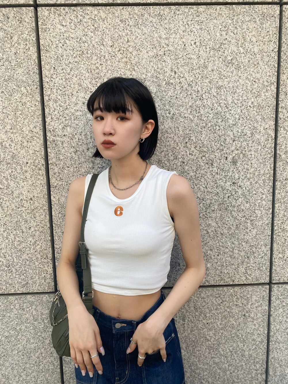 ブラック系のサンダル、ブルー系のデニムパンツ、ホワイト系のタンクトップを着用したレディースの夏コーディネートの6枚目の写真