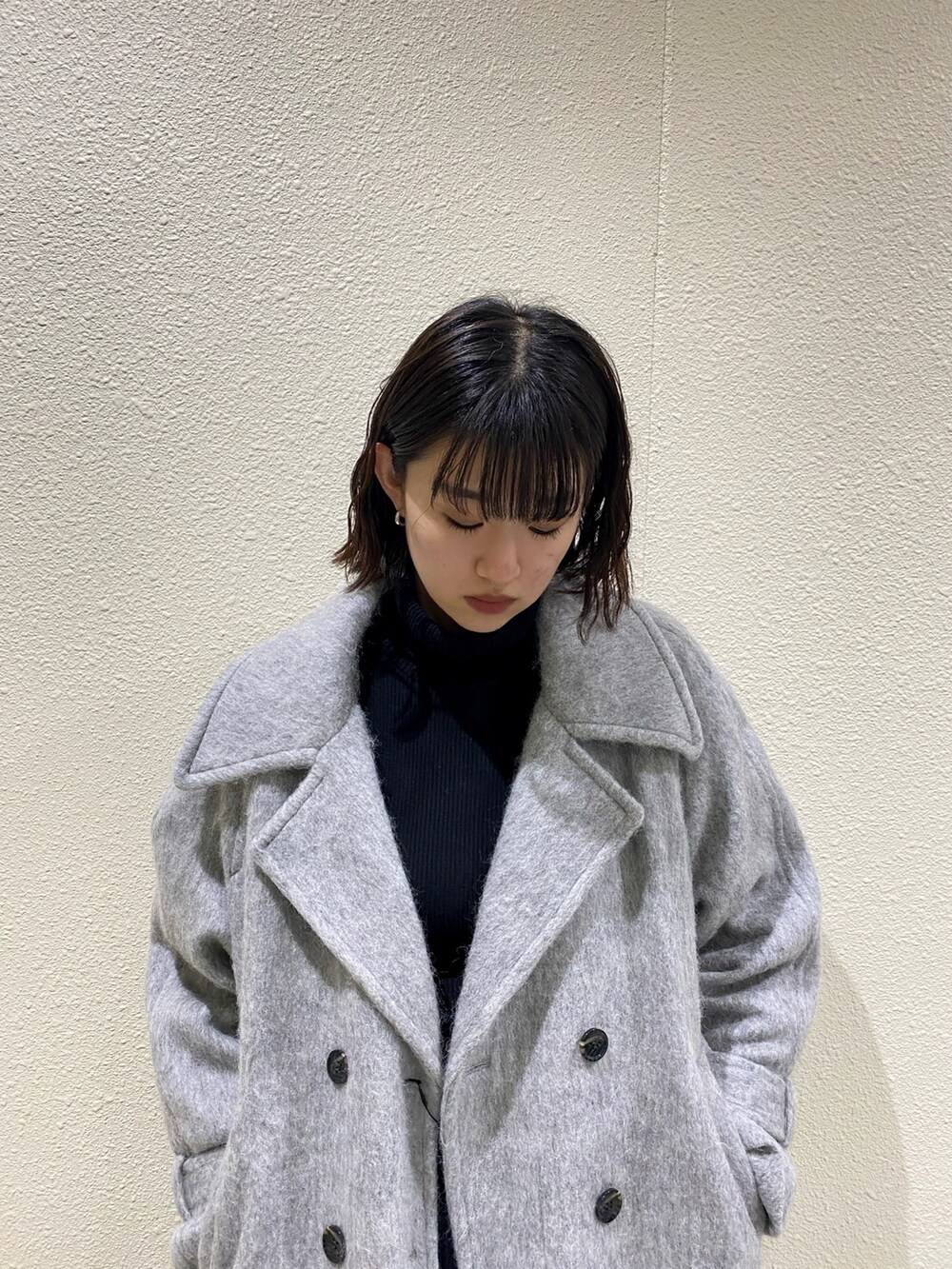 ブラック系のブーツ、グレー系のチェスターコート、ブラック系のスカートを着用したレディースの冬コーディネートの5枚目の写真