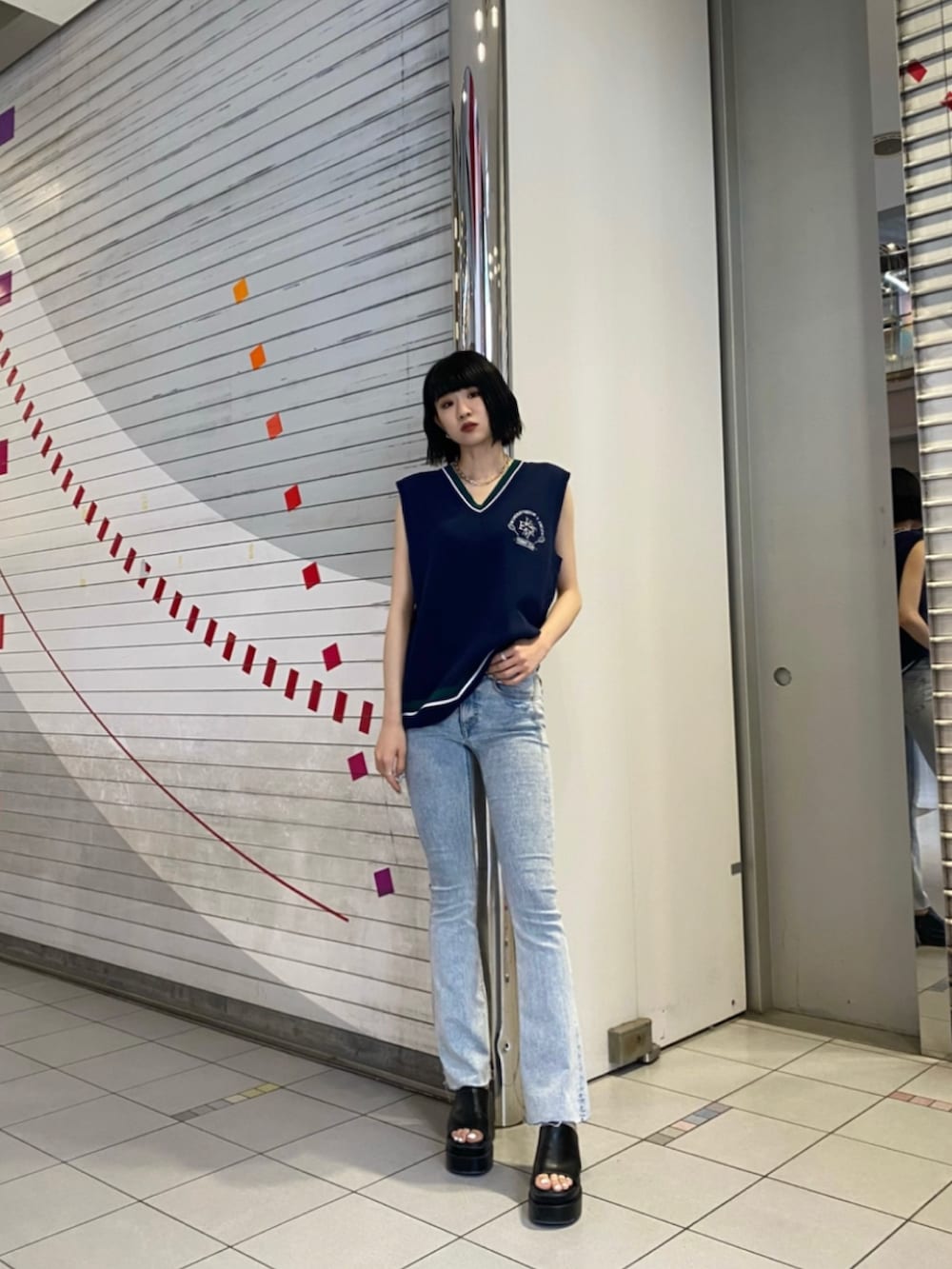 ブラック系のサンダル、ブルー系のデニムパンツ、ブルー系のベストを着用したレディースの春コーディネートの2枚目の写真