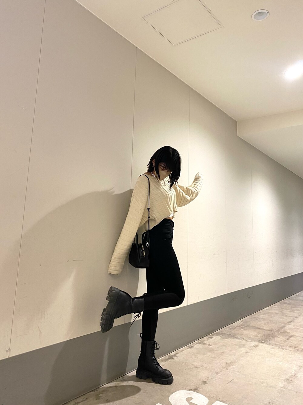 ブラック系のブーツ、ブラック系のデニムパンツ、ホワイト系のニット/セーターを着用したレディースの春コーディネートの5枚目の写真