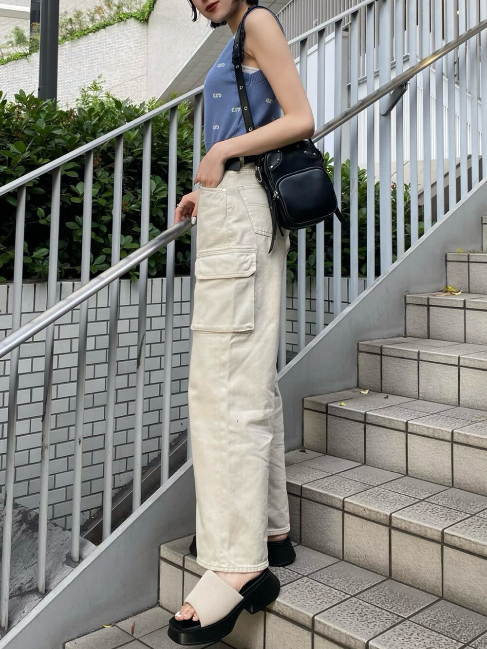 ブラック系のショルダーバッグ、ホワイト系のサンダル、ホワイト系のデニムパンツを着用したレディースの春コーディネートの4枚目の写真