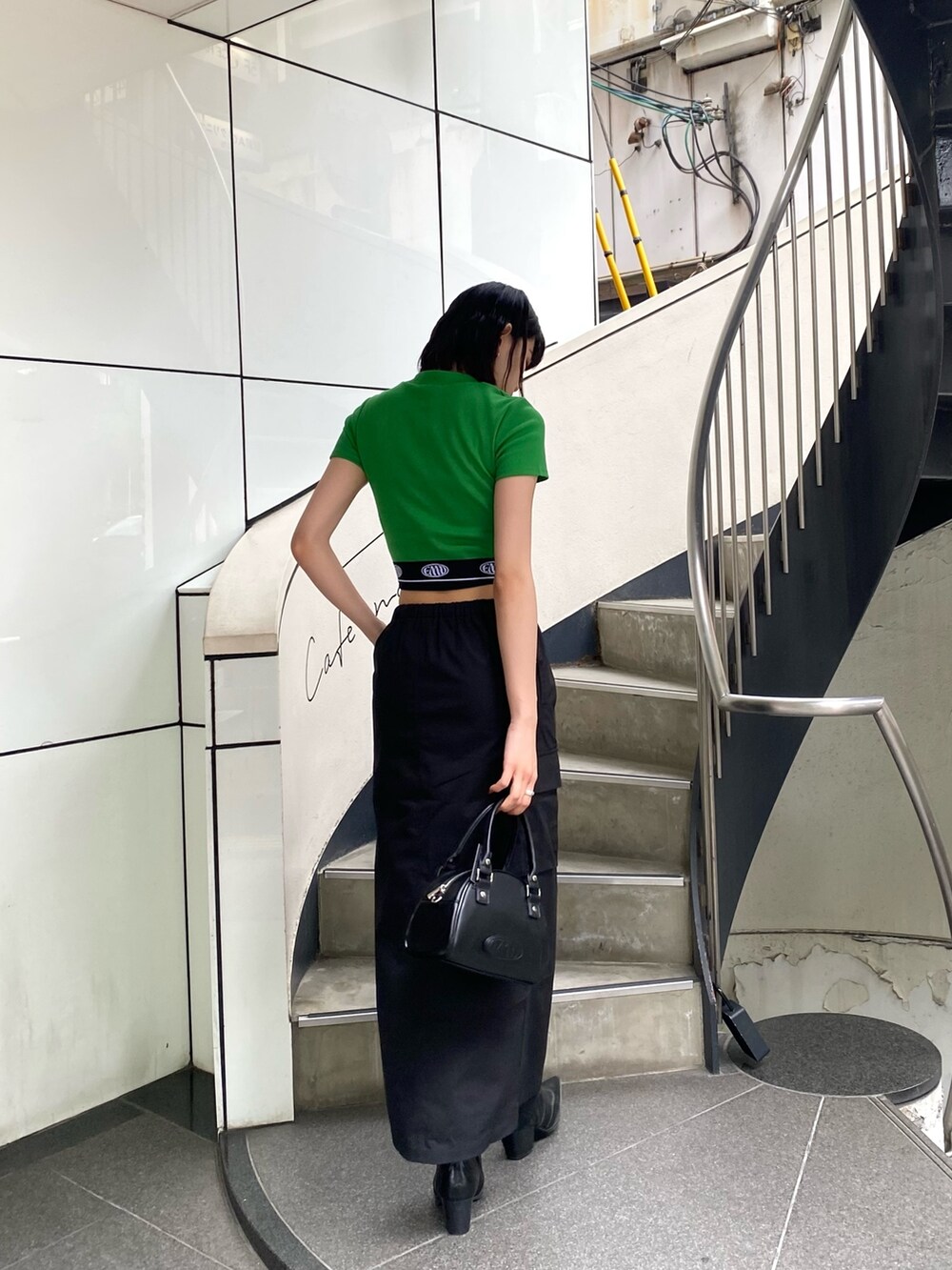 ブラック系のスカート、ブラック系のハンドバッグ、グリーン系のTシャツ/カットソーを着用したレディースの春コーディネートの4枚目の写真