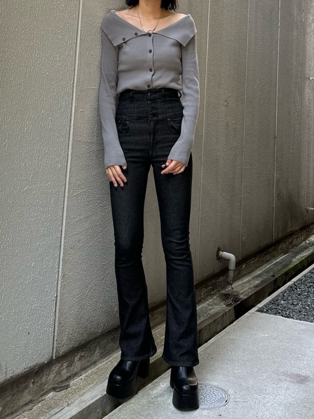 ブラック系のデニムパンツ、ブラック系のブーツ、グレー系のニット/セーターを着用したレディースの秋コーディネートの2枚目の写真