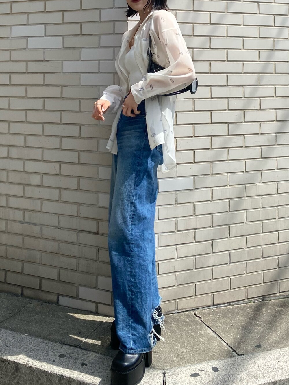 ブラック系のサンダル、ブラック系のハンドバッグ、ブルー系のデニムパンツを着用したレディースの春コーディネートの4枚目の写真