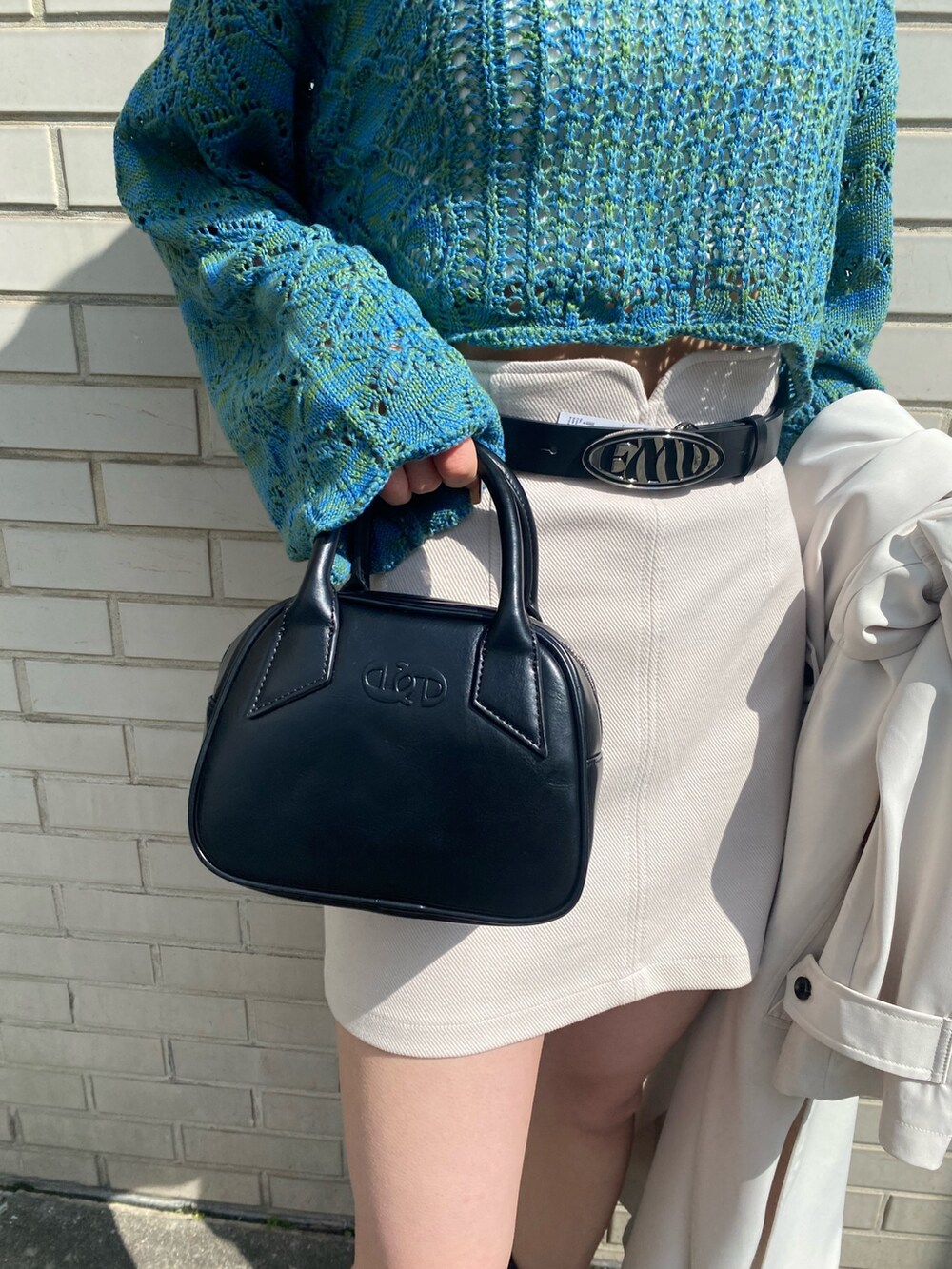 ホワイト系のスカート、ブルー系のニット/セーター、ホワイト系のトレンチコートを着用したレディースの春コーディネートの10枚目の写真