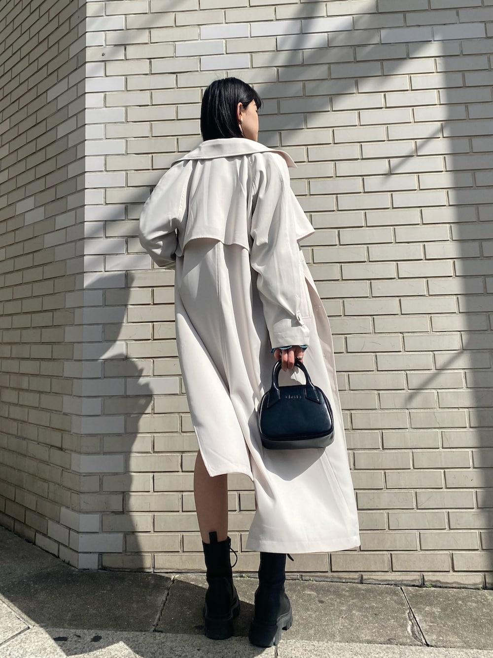ホワイト系のスカート、ブルー系のニット/セーター、ホワイト系のトレンチコートを着用したレディースの春コーディネートの6枚目の写真