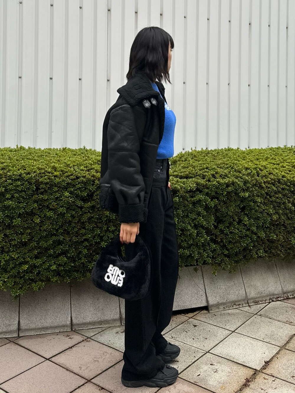 ブラック系のデニムパンツ、ブラック系のハンドバッグ、ブラック系のムートンコートを着用したレディースの冬コーディネートの4枚目の写真