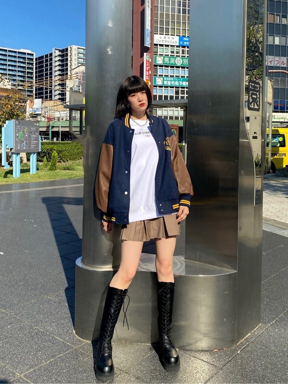 ブラック系のブーツ、ブルー系のブルゾン、ベージュ系のスカートを着用したレディースの秋コーディネートの2枚目の写真