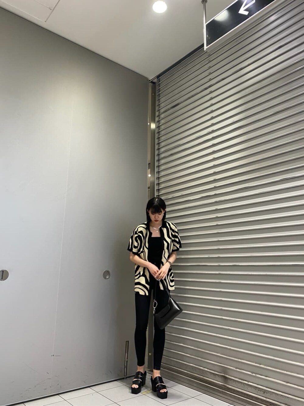 ブラック系のニット/セーター、ブラック系のサンダル、ブラック系のデニムパンツを着用したレディースの夏コーディネートの3枚目の写真