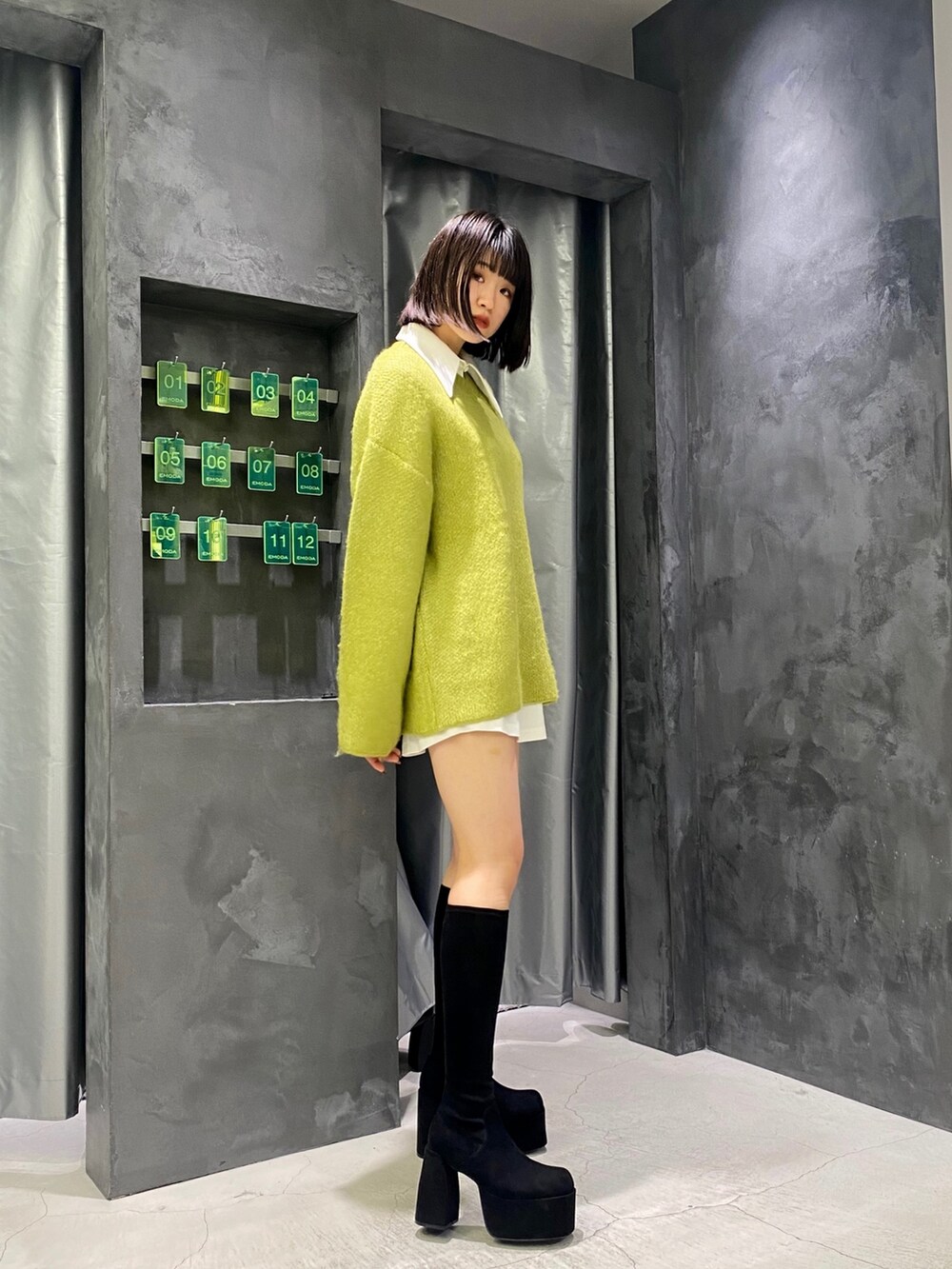 ブラック系のブーツ、イエロー系のニット/セーター、ホワイト系のワンピースを着用したレディースの冬コーディネートの4枚目の写真