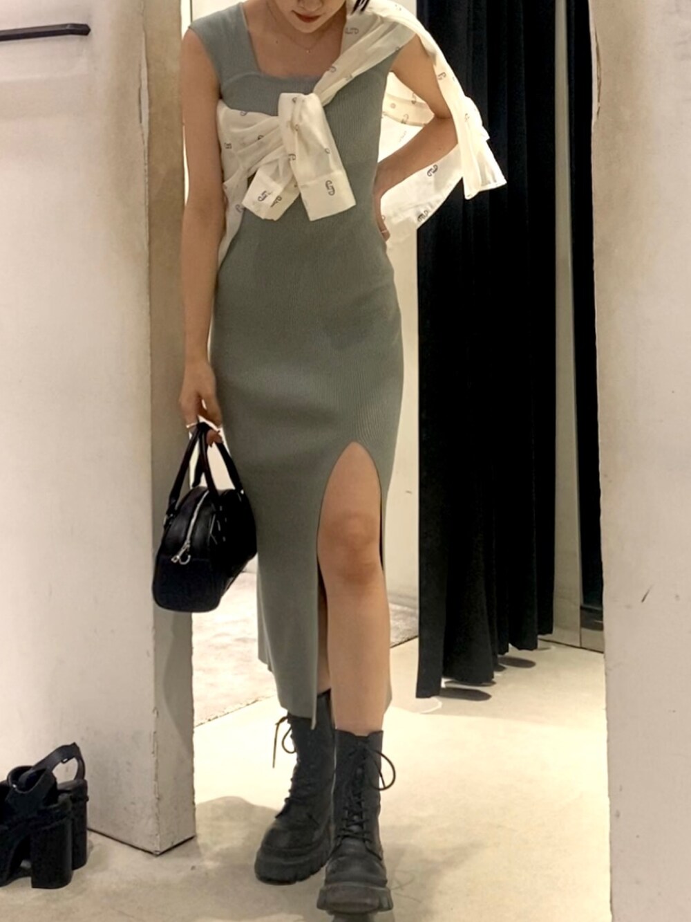 ブラック系のハンドバッグ、ブラック系のブーツ、グレー系のワンピースを着用したレディースの春コーディネートの4枚目の写真