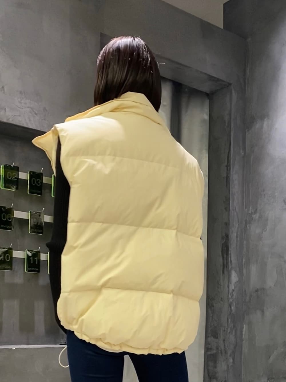 ブルー系のデニムパンツ、ブラック系のブーツ、ホワイト系のダウンベストを着用したレディースの秋コーディネートの4枚目の写真